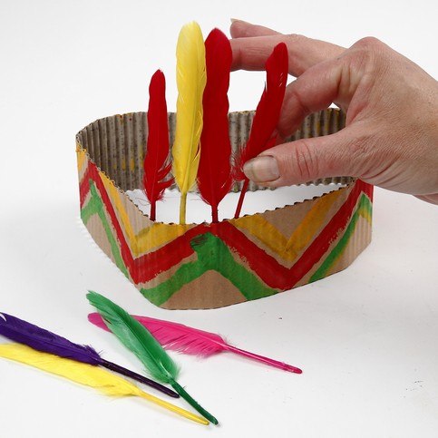 A Head Dress made from Painted Corrugated Board, decorated with Feathers