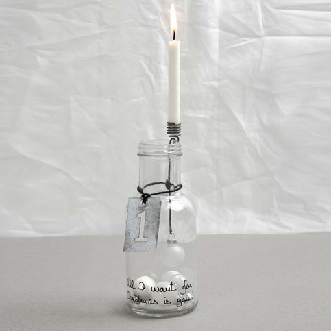 A Bottle with a decorated Candle Holder and a Metal Sign