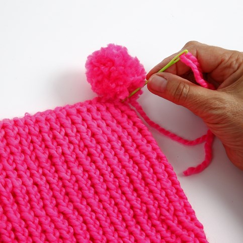 A Hat with two Pom Poms knitted on a Knitting Loom