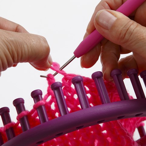 A Hat with two Pom Poms knitted on a Knitting Loom