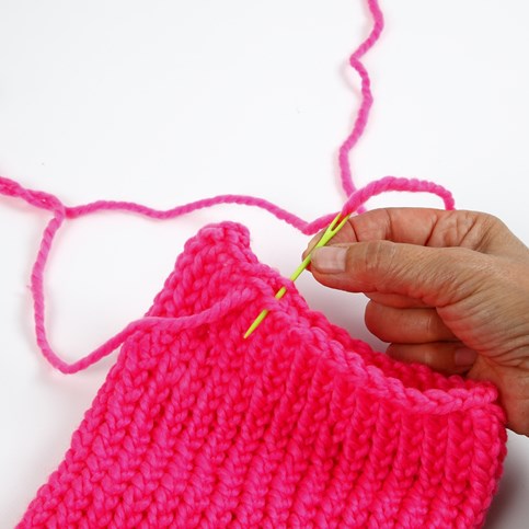 A Hat with two Pom Poms knitted on a Knitting Loom